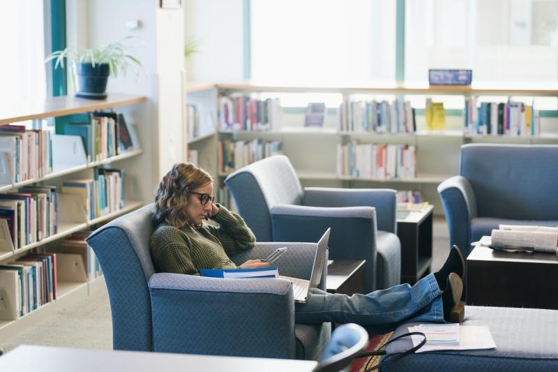 A woman works on her laptop in a soft chair at Matthews-Fuller