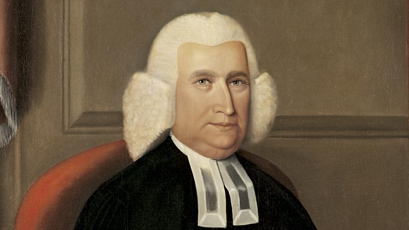 white man in wig with black robe, seated