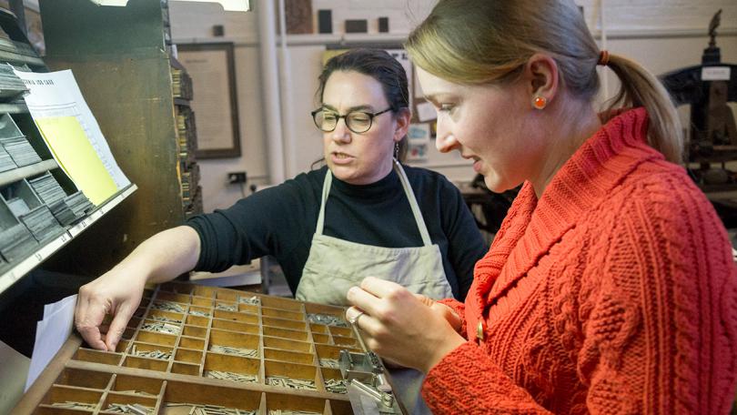 An instructor showing a student printmaking tools