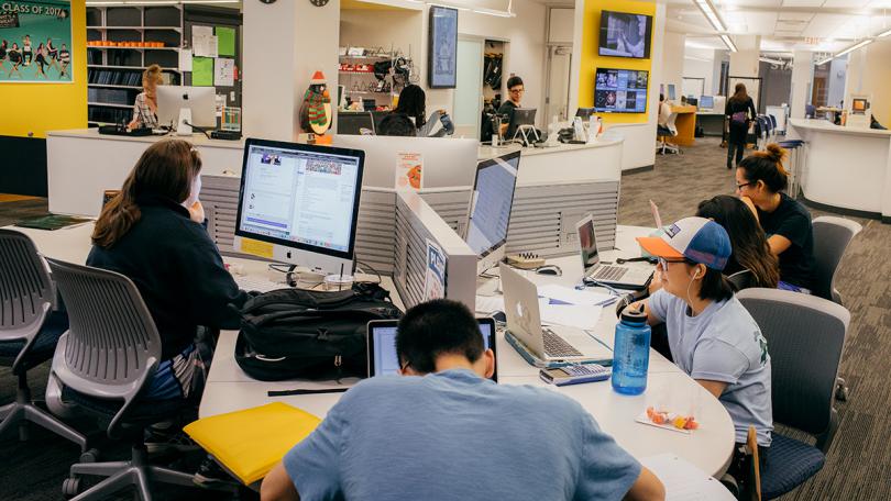 Students sitting at a table looking at computers