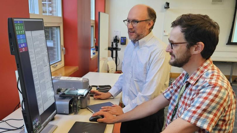 two library staff members look at newspaper digital resource