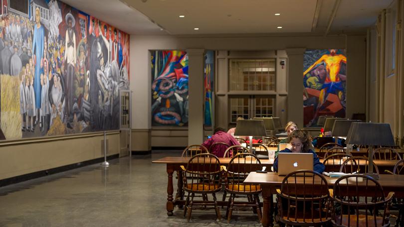 Murals on the walls and students sitting tables