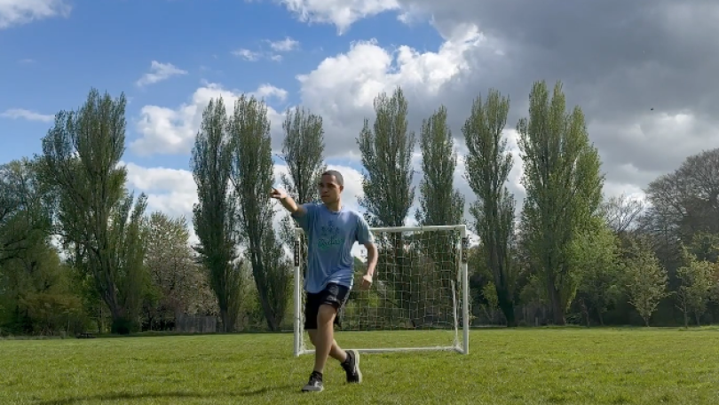 Jason Davis '25 points to the left of the camera while playing on a soccer pitch