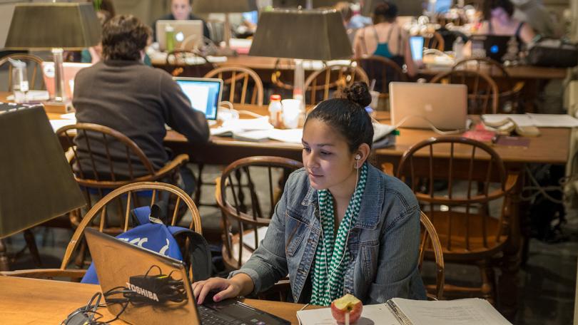 Female student sitting at a table with laptop open headphones on