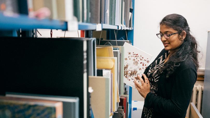 Student taking a book out of a book shelf