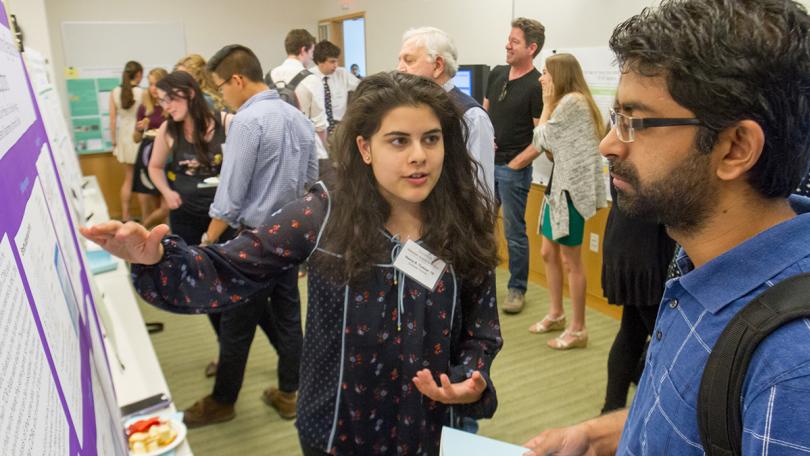 Student shows her poster to another poster