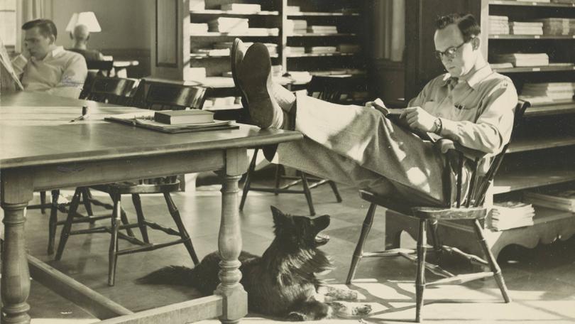 Black and white photo of a student putting feet on table in Baker-Berry Library