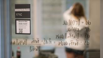 A student writes on the glass walls of a study room in Baker-Berry Library at Dartmouth College