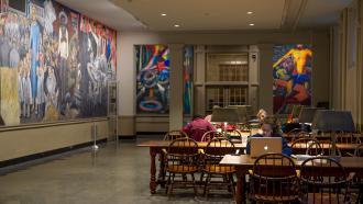 Murals on the walls and students sitting tables