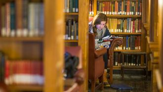 Student studying in a space surrounded by shelves
