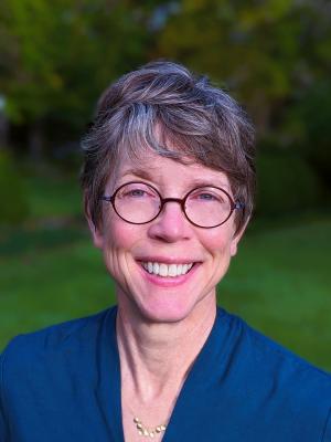 portaint of a white skinned woman smiling outdoors with glasses