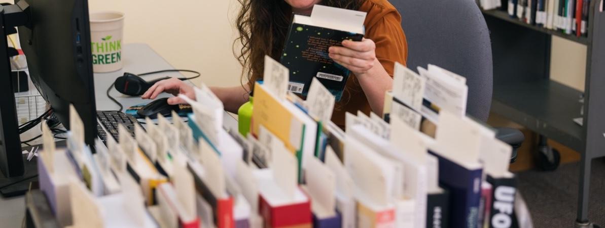 library staff member processes new books in acquisitions department