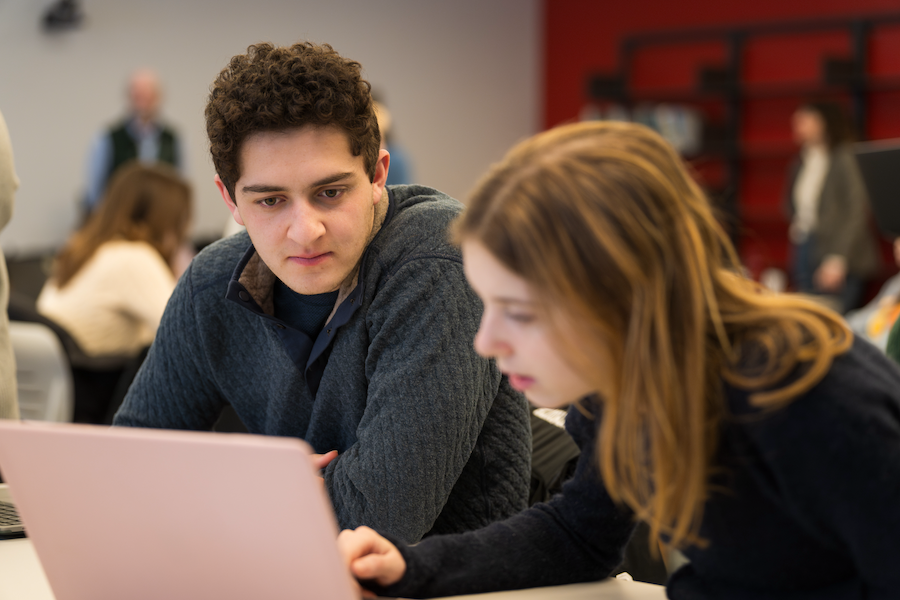 two students collaborate on their laptops