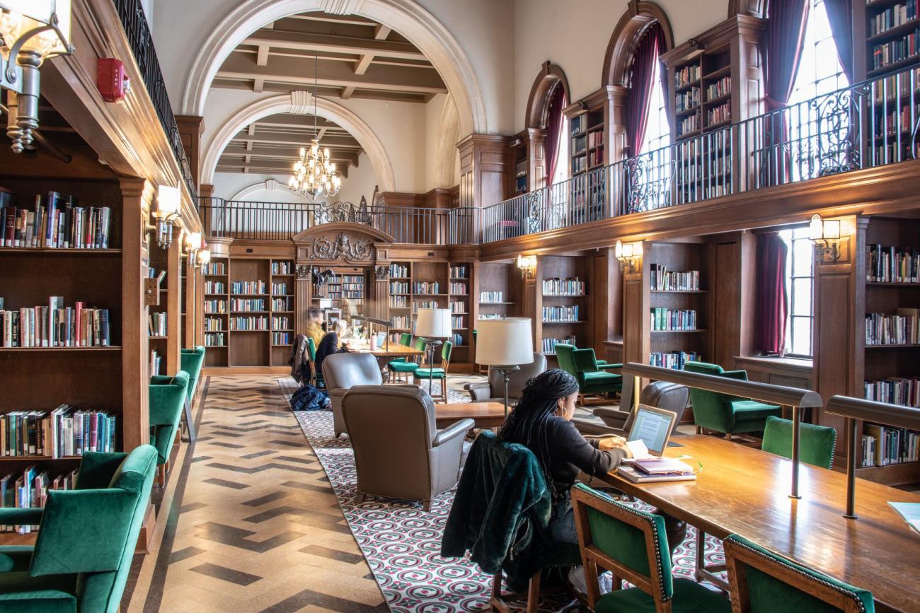Person studying at long table in a library.