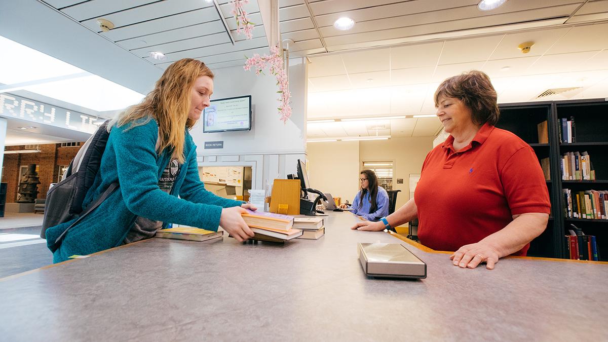 Student returns books to the Baker-Berry Circulation Desk