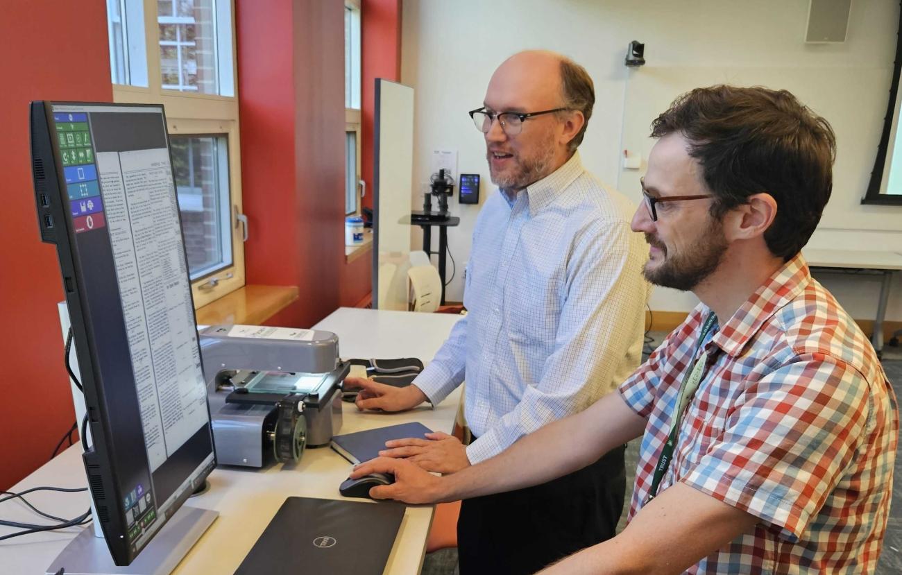 two library staff members look at newspaper digital resource