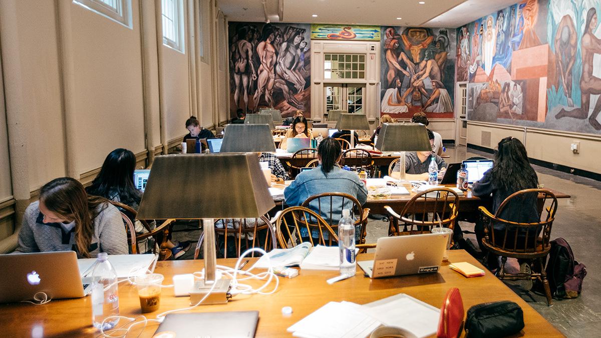 Students studying at desks and laptops on desks