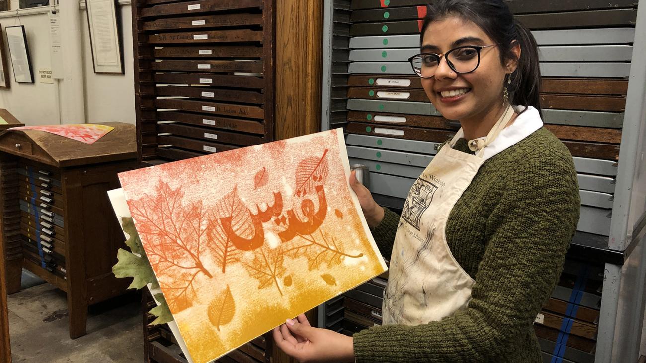 student holding up an orange poster she printed