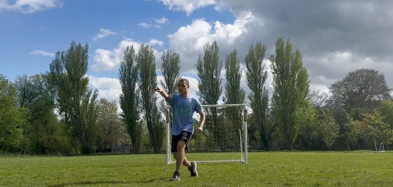 Jason Davis '25 points to the left of the camera while playing on a soccer pitch
