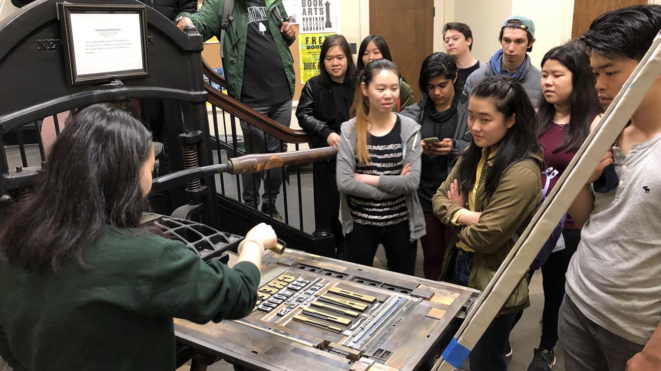 Students around a press with one printing 