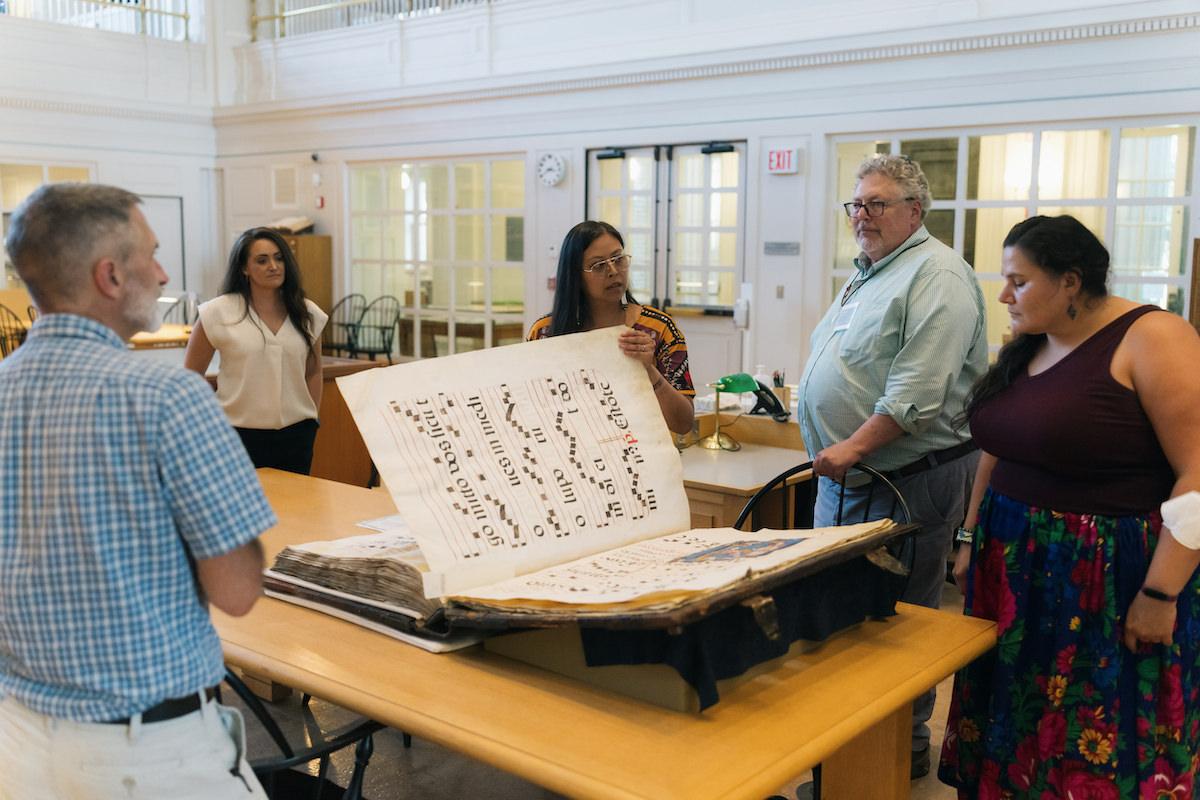 Peter Carini left watches on as Jennifer O'Neal, Miranda Belarde-Lewis, and Veronica Pipestem look at an Indigenous cultural item in the Rauner Special Collections Library