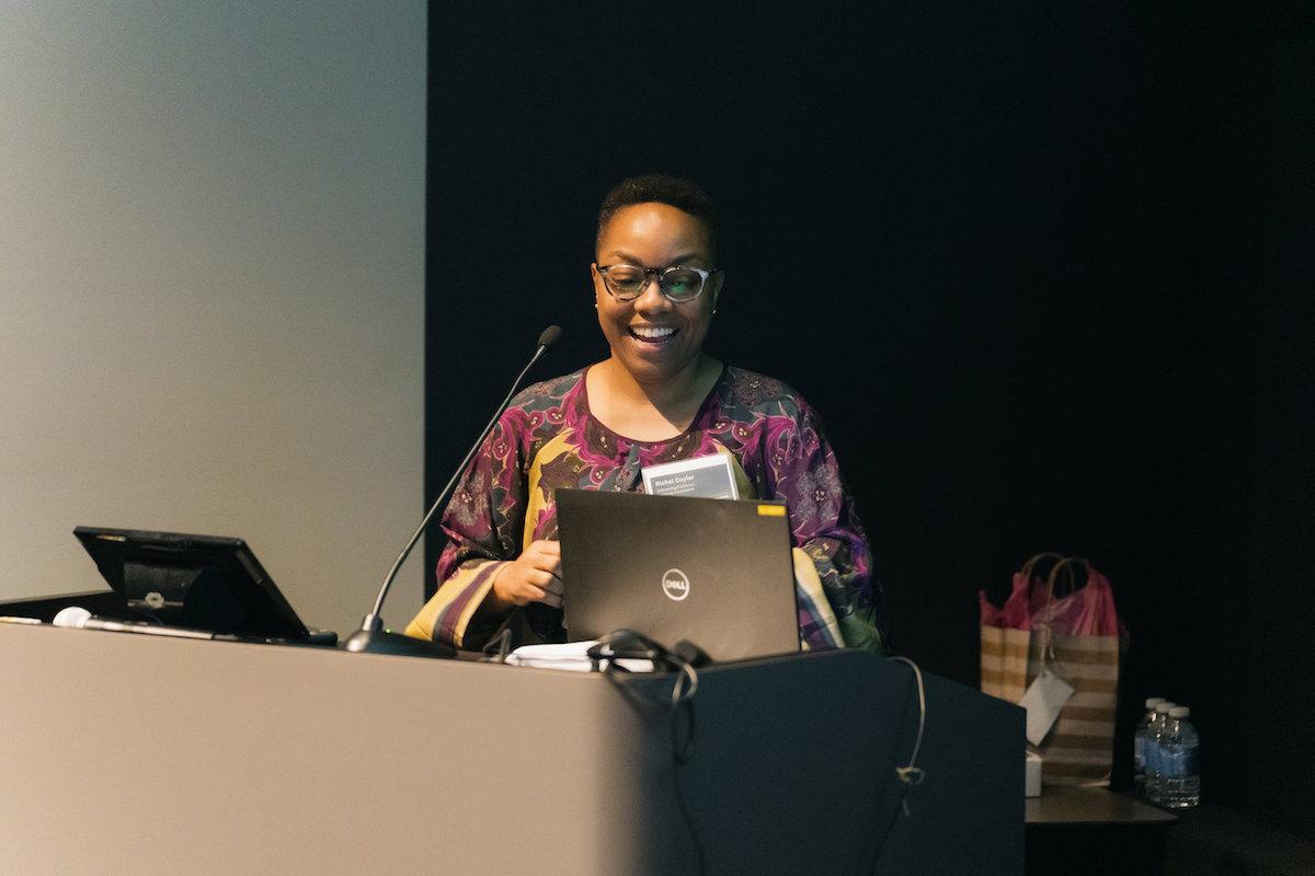 Richel Cuyler, co-organizer of the Advancing Pathways Colloquium stands at a podium smiling