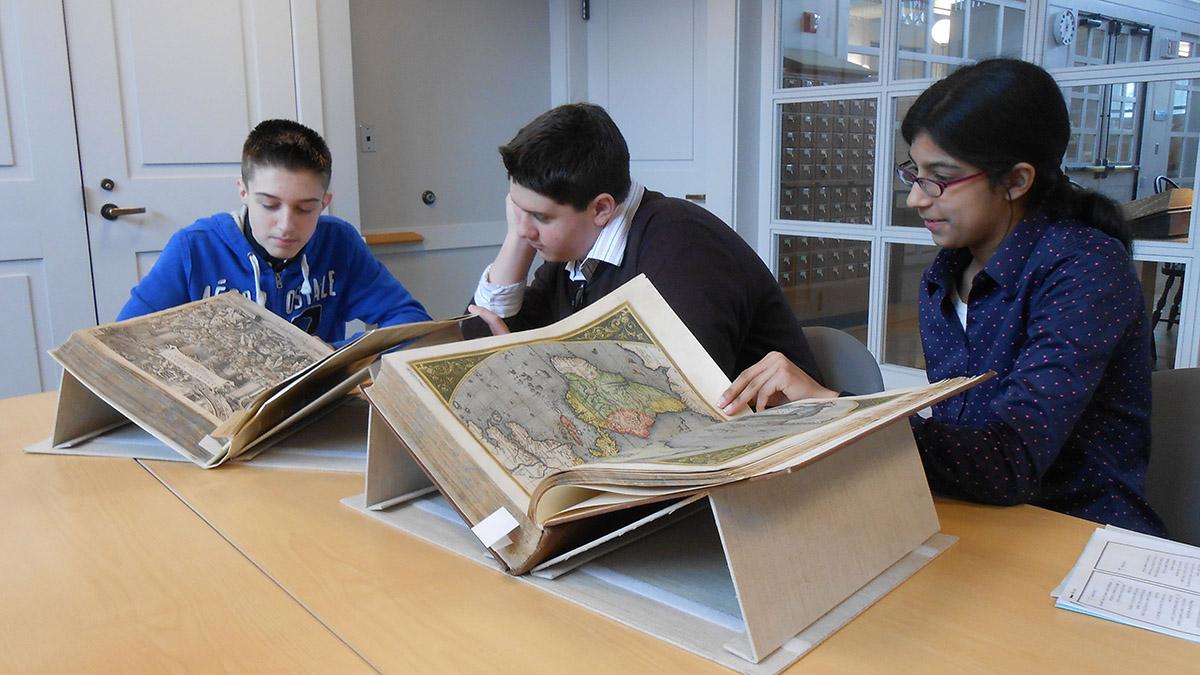 Students look at a large book in Rauner
