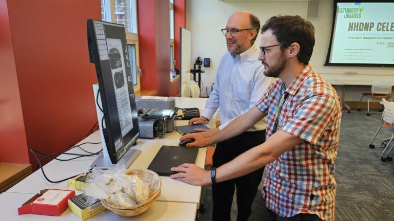 Kent Randall and Toben Traver look at microfilm from the newspaper digitization project