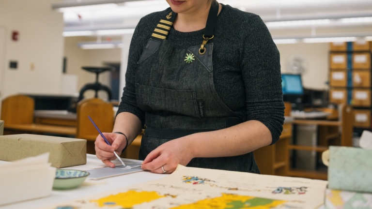 member of preservation team works on an item in the conservation studio