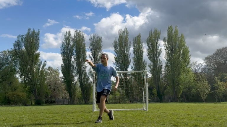 Jason Davis '25 points to the left of the camera while playing on a soccer pitch